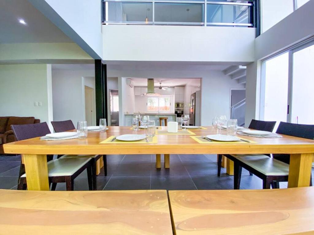 Big 5BR Home for an epic time in Riviera Maya في أكومال: غرفة طعام مع طاولة وكراسي خشبية