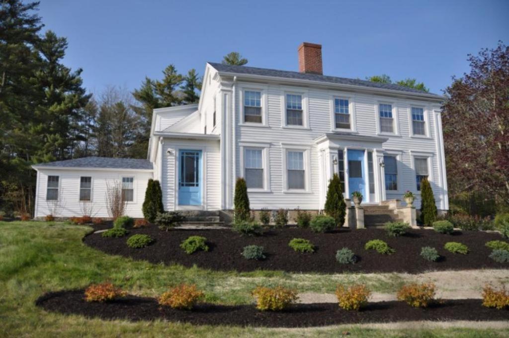 a white house with a garden in front of it at 2 River Road Inn Cottages in Cape Neddick