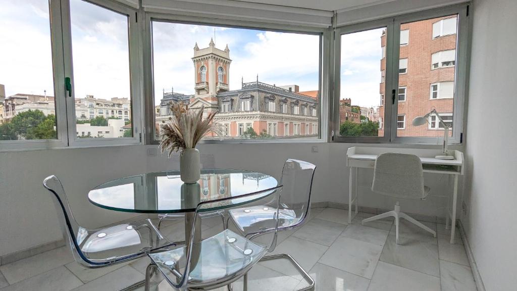 una mesa y sillas en una habitación con vistas a un edificio en DFLAT Escultor Madrid Apartments, en Madrid