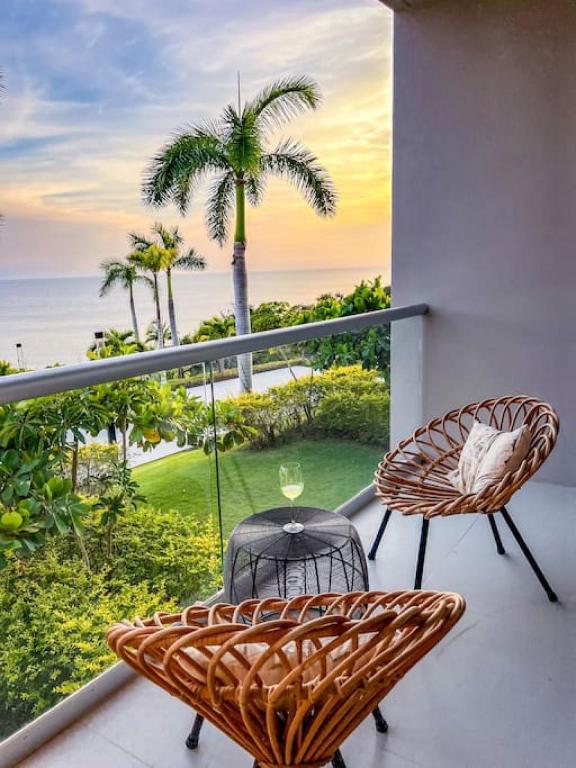 a balcony with a table and chairs and a palm tree at Spectacular Ocean front 5BR condo in Bolongo in Punta Mita