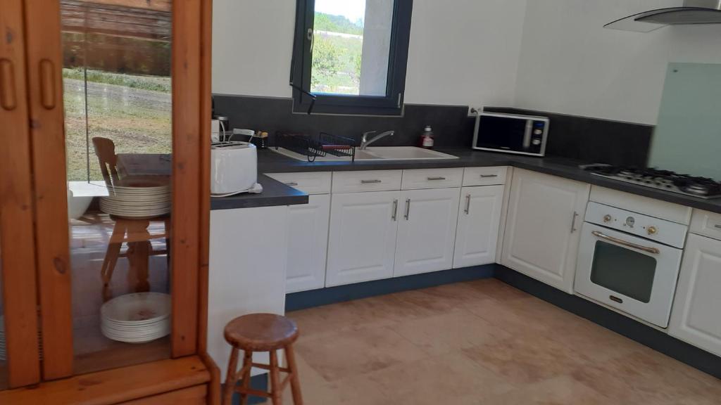 une cuisine avec des armoires blanches et un évier dans l'établissement Cabanon le sarazin, à Puyvert