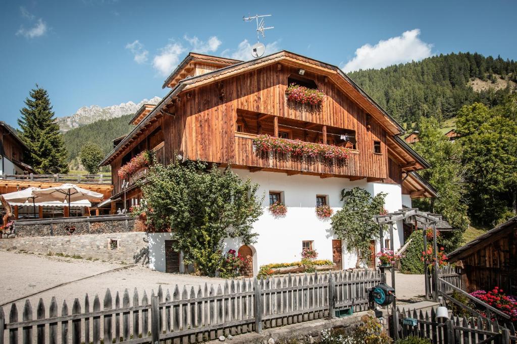 uma casa de madeira com uma cerca em frente em Agriturismo Lüch de Vanc em San Martino in Badia