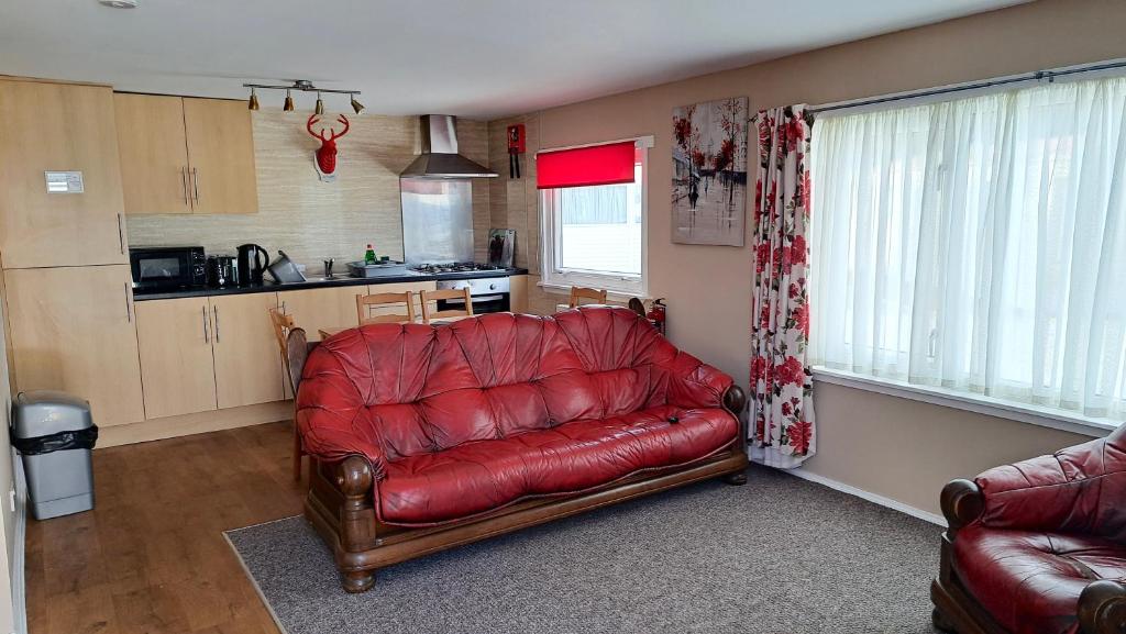 a living room with a red leather couch and a kitchen at 3 Bedroom Self-Catering Chalet in Steps