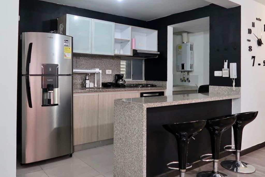 uma cozinha com um frigorífico de aço inoxidável e bancos de bar em 3 Bed apartment, near El Dorado Airport em Bogotá