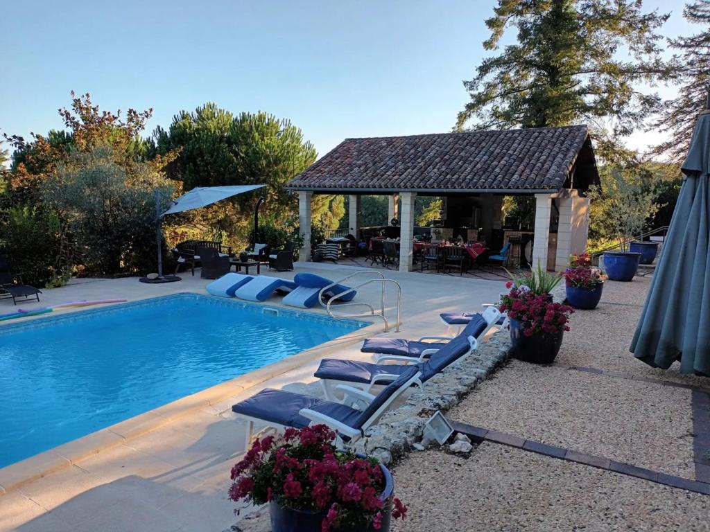 a swimming pool with lounge chairs and a gazebo at Gîtes et chambres croix du sud in Saint-Amand-de-Vergt