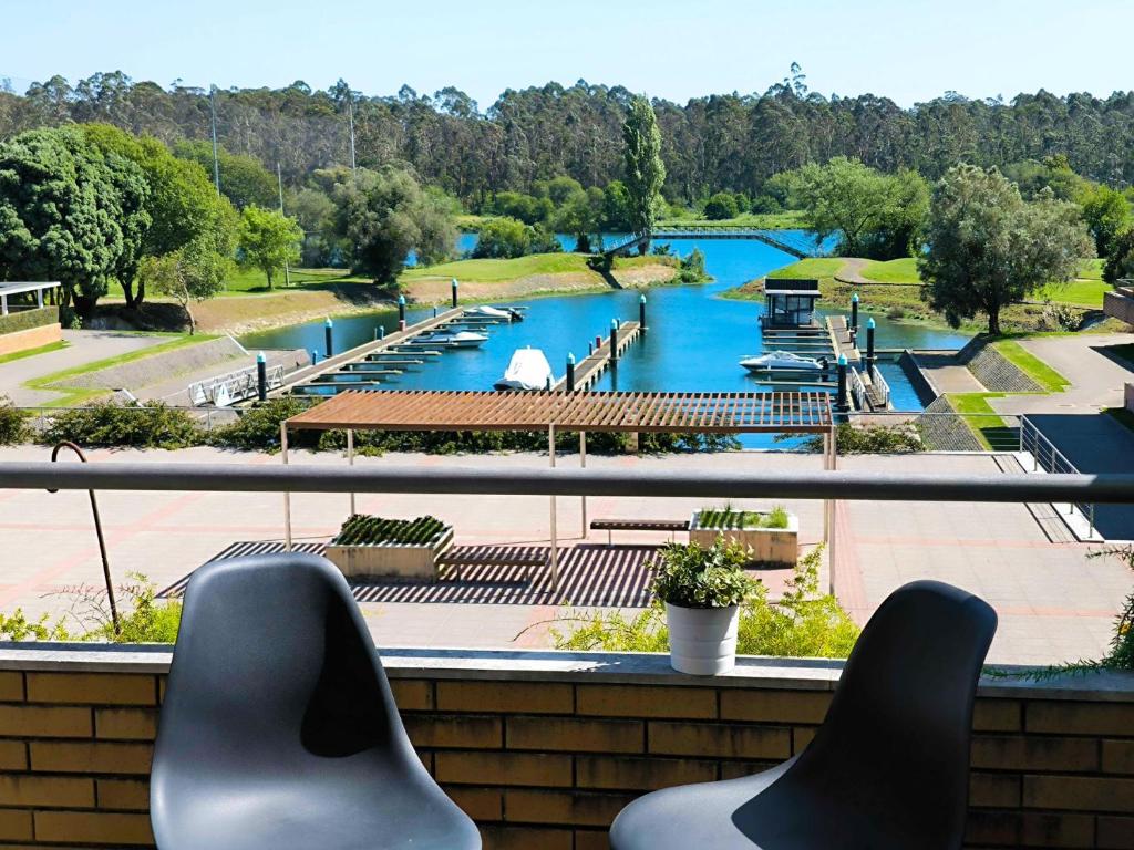 two chairs sitting on a balcony looking out at a river at Apartamento Esposende Quinta da Barca in Barca do Lago