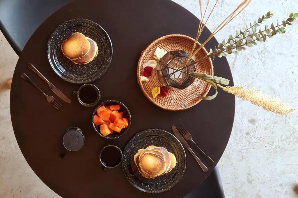 una mesa con platos de comida y una cesta de fruta en Cabañas Grasshopper SHIELD, en Tepoztlán