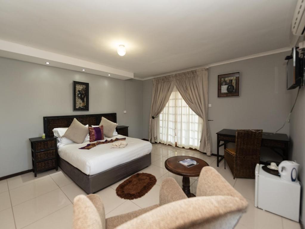 a bedroom with a bed and a table and chairs at Mumses Guest House in Ramotswa