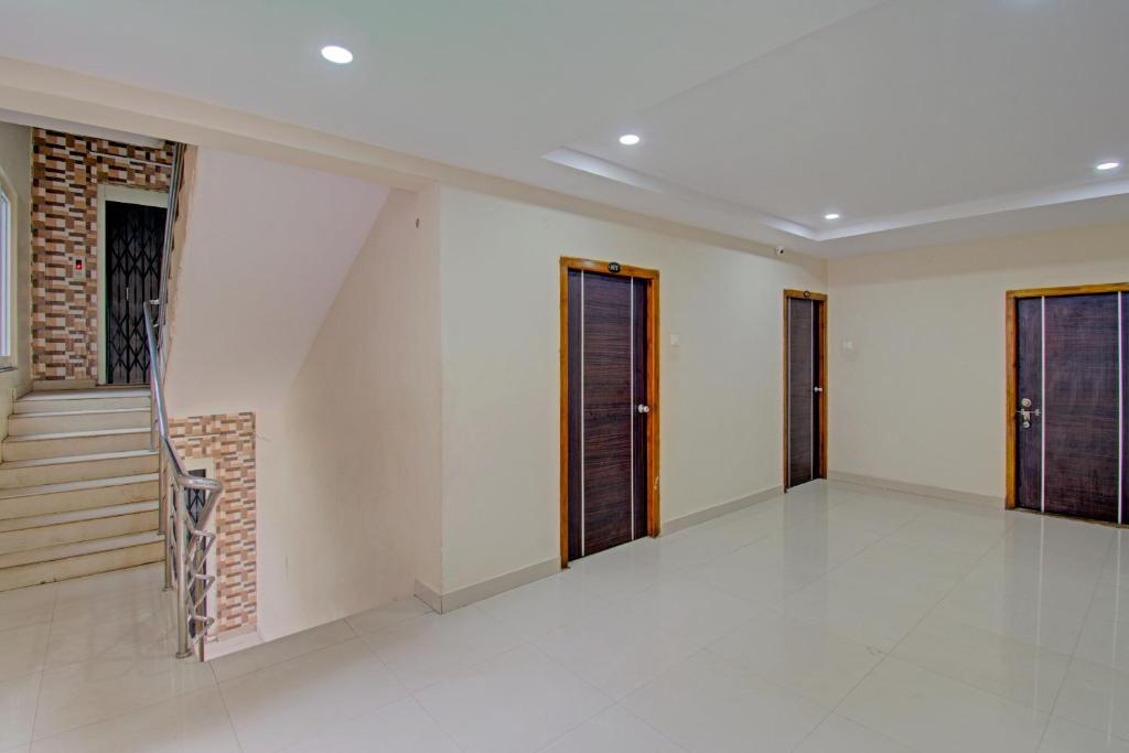 Habitación con paredes blancas y puertas de madera. en Super OYO Flagship 80823 Hotel Sitara Grand, en Visakhapatnam