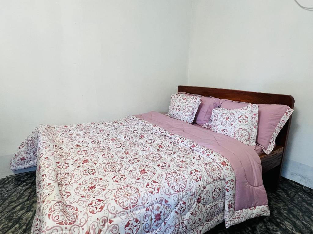 a bed with pink and white sheets and pillows at Home Stays Juba in Juba