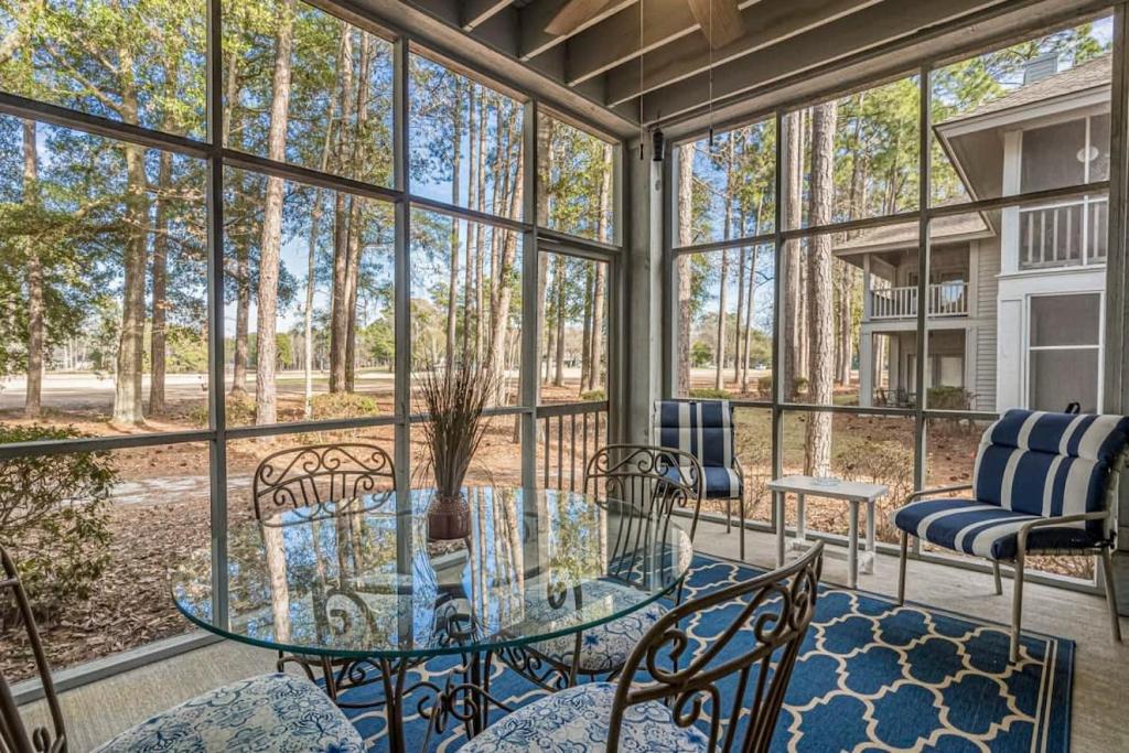 a screened porch with a glass table and chairs at Teal lake 1311 in North Myrtle Beach