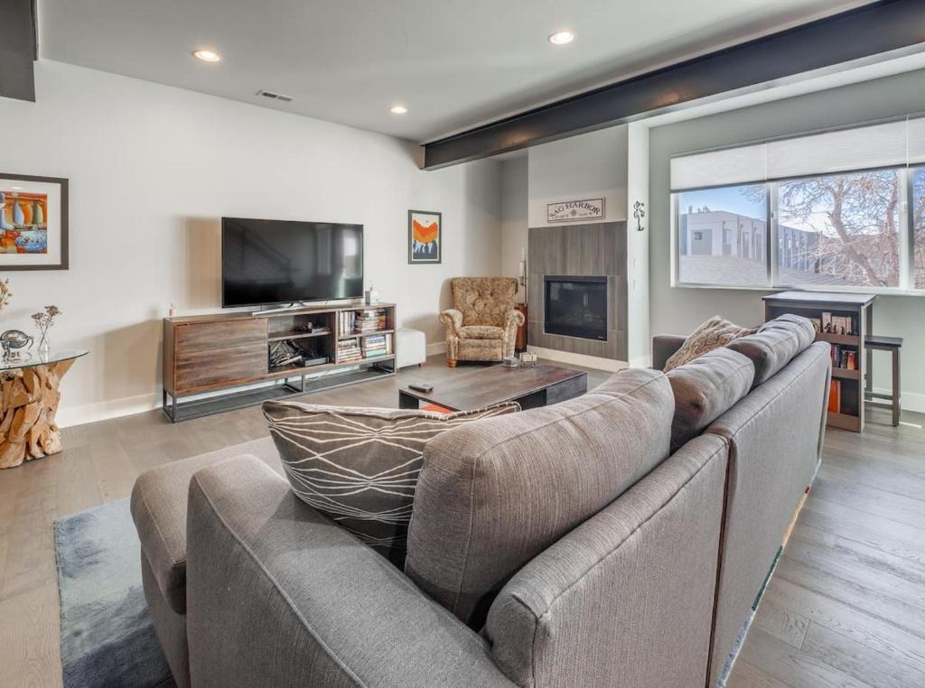 a living room with a large couch and a tv at Roof Top Deck w Views Walk to Empower Field in Denver