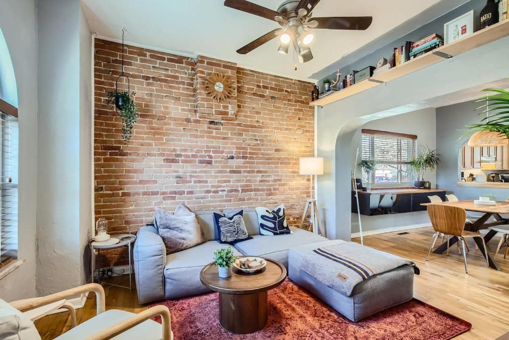 a living room with a couch and a brick wall at RiNo Charmer 2bd Family Home Ev Charger in Denver