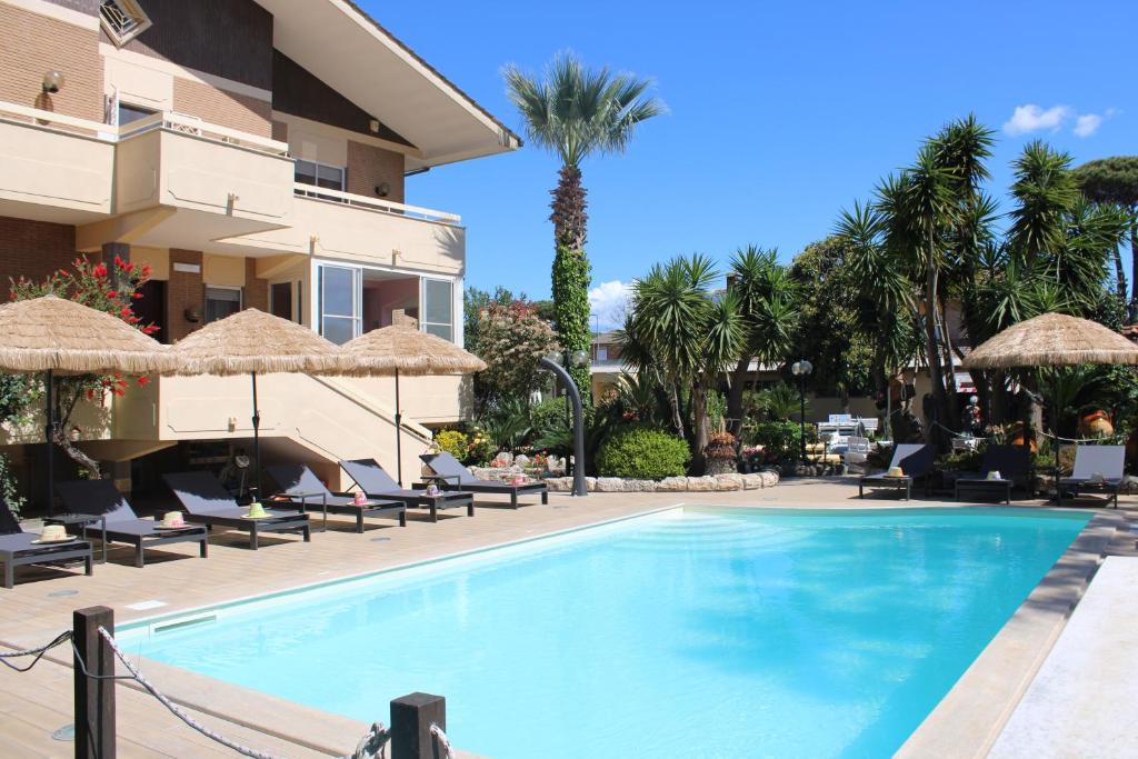 een zwembad met stoelen en parasols naast een gebouw bij Resort la Magnolia in Anzio