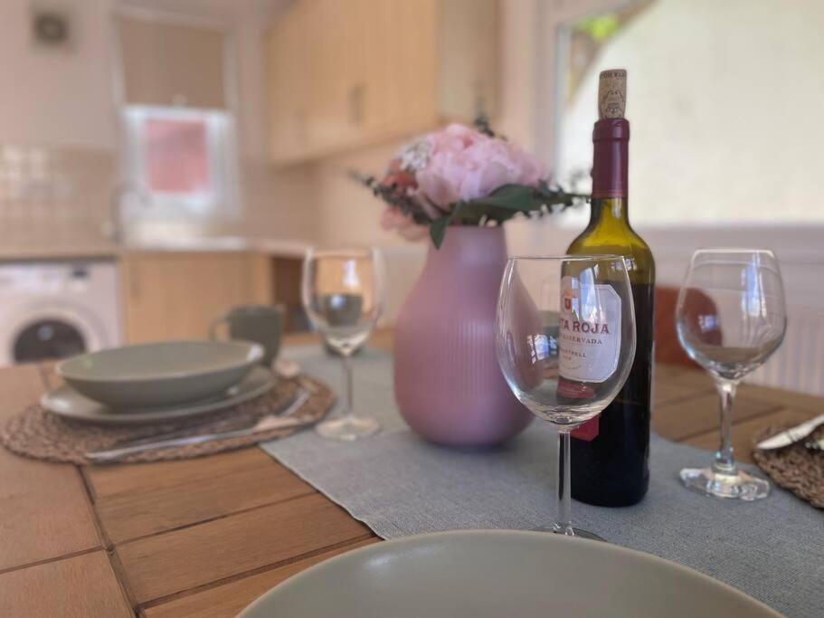 a table with a bottle of wine and two wine glasses at Charming 3-Bed Home in Halsted in Halstead