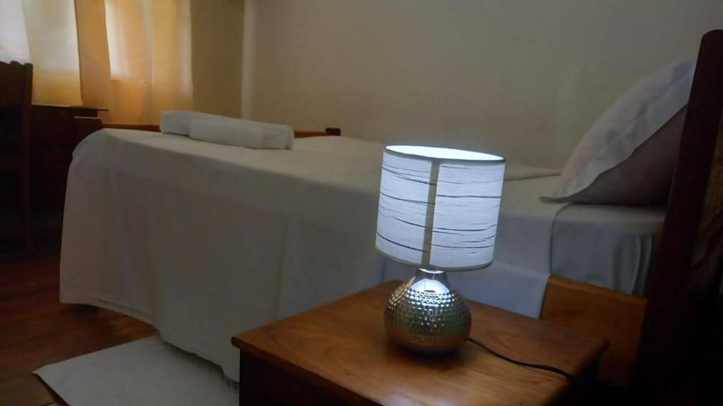 une lampe assise sur une table à côté d'un lit dans l'établissement Residencial Arca de Noé, à Santo António
