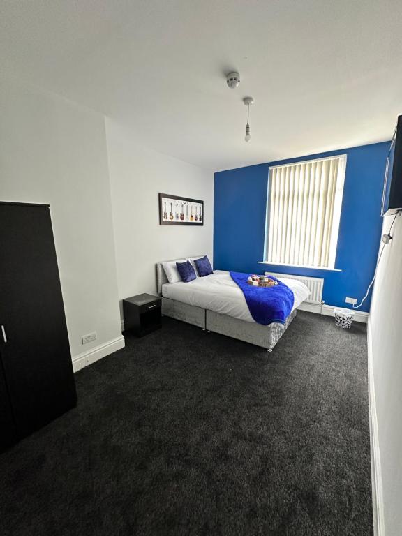 1 dormitorio con cama y pared azul en Quirky Oasis Queens, en Liverpool