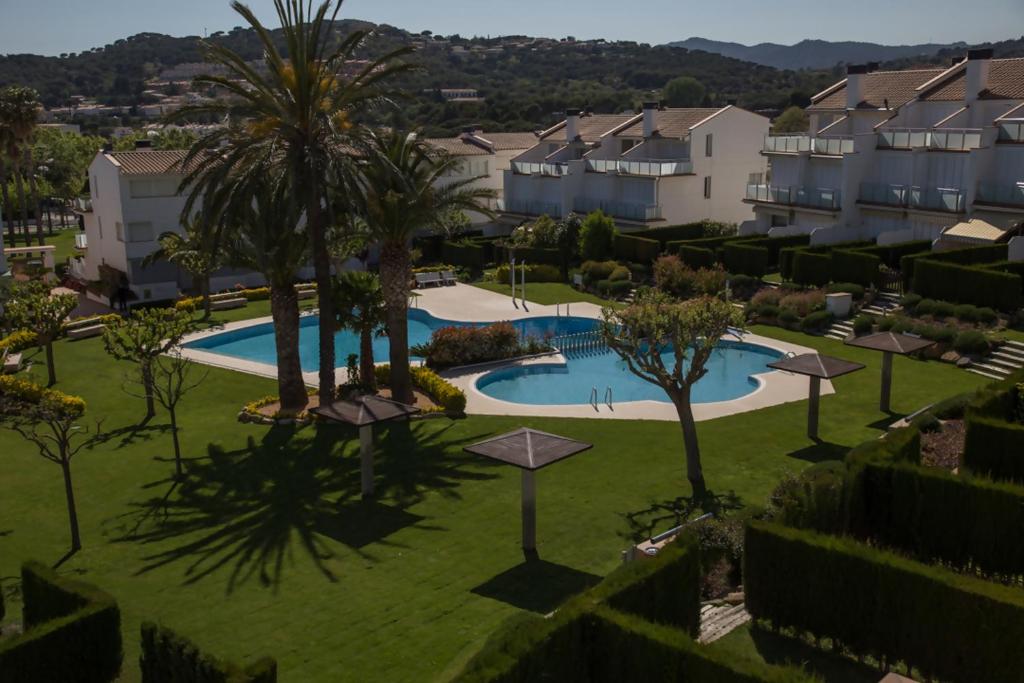 an apartment complex with a swimming pool and palm trees at Casa 7 Parc Sant Ramon descanso y armonía in Platja d'Aro