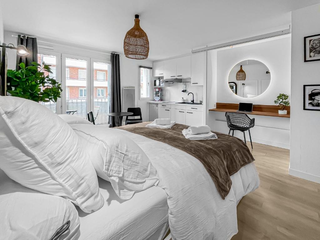 - une chambre blanche avec un grand lit et une cuisine dans l'établissement Balnéo-Ciné-Centre Historique à Troyes, à Troyes