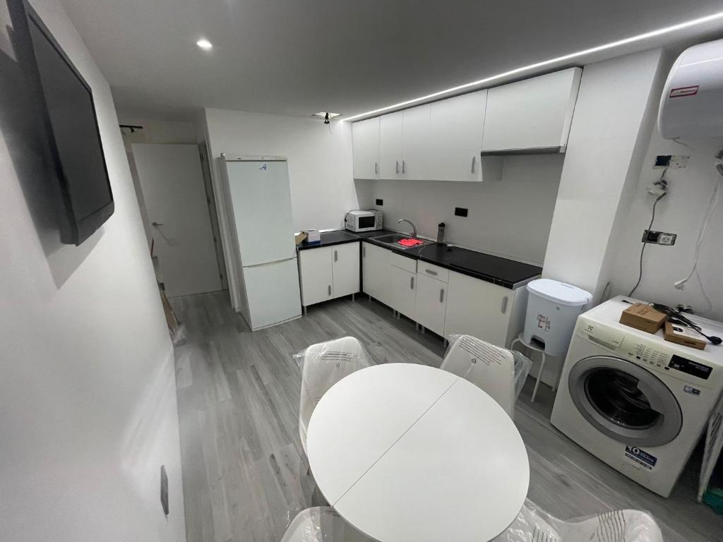 een kleine keuken met een witte tafel en een wasmachine bij Inverpol in Granada