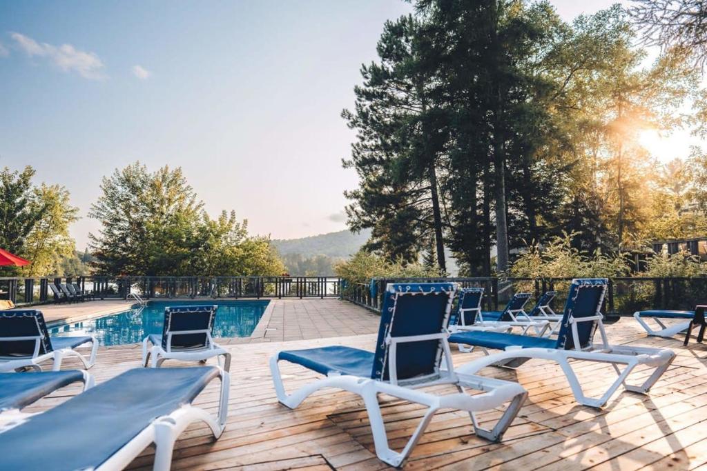 a group of chairs sitting on a deck next to a pool at Spacious log cottage Resort access in Lac-Superieur