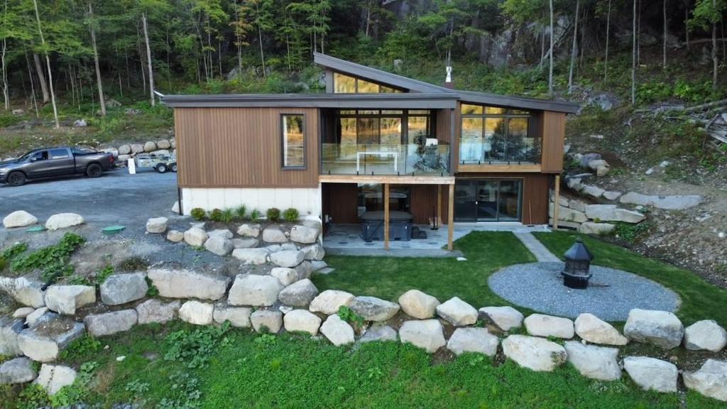 a small house with a stone wall at Lakeview Mid Century Luxury Cottage in Sainte-Adèle
