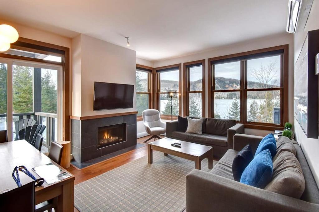 a living room with a couch and a fireplace at Waterfront condo with magnificent view in Lac-Superieur