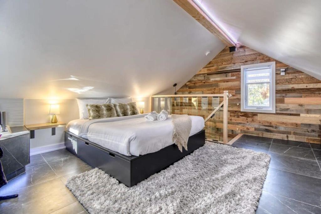 1 dormitorio con 1 cama y pared de madera en Le mini chalet en Sainte Anne des Lacs