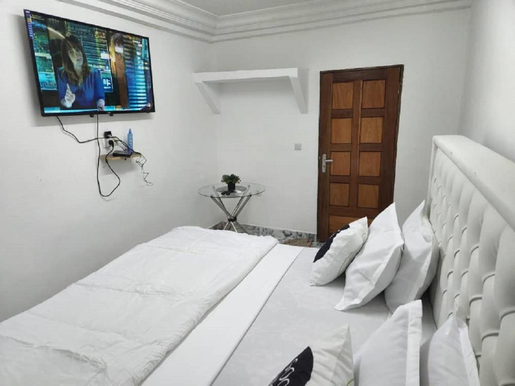 a bedroom with a bed with a flat screen tv on the wall at Chambre Meublée à Douala, Bonapriso - Armée del'air in Douala