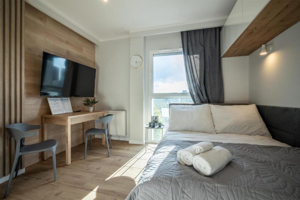 Schlafzimmer mit einem Bett, einem Schreibtisch und einem TV in der Unterkunft WiguryTower Apartaments 65 in Łódź