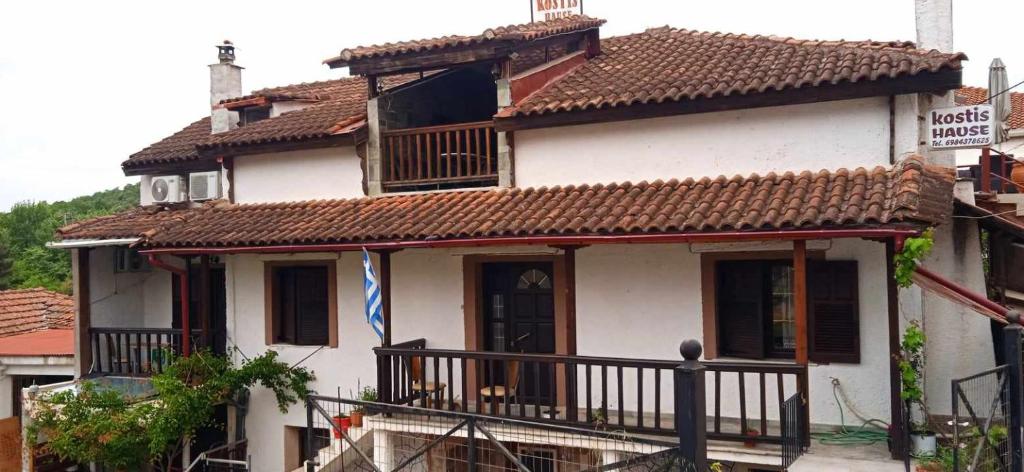 a white house with a brown roof and a balcony at Kostis Hause in Kastraki