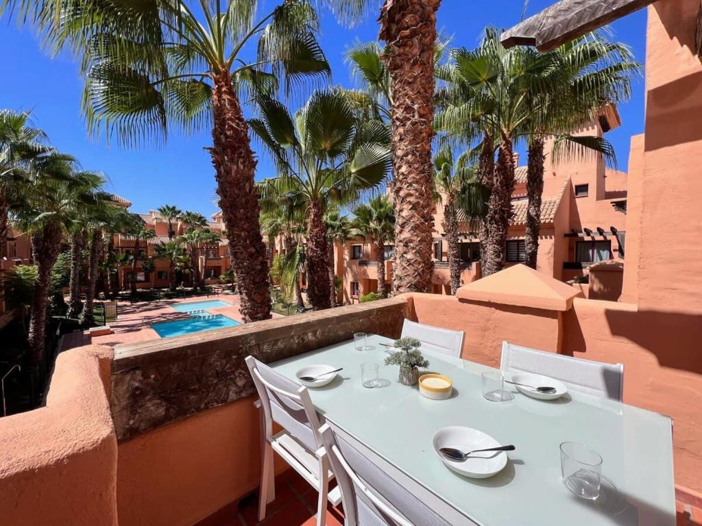 a white table and chairs on a balcony with palm trees at Modern 2 Bedroom Beachside Apartment NR72 in Los Alcázares
