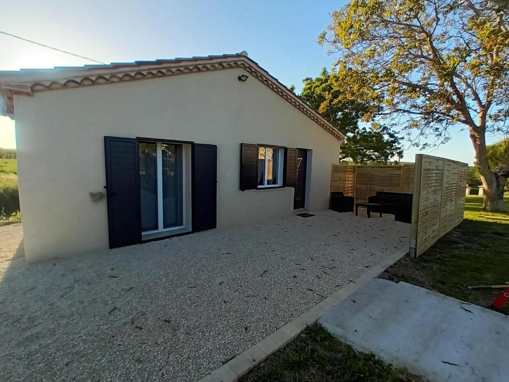 een klein wit huis met zwarte deuren en een tuin bij Petite Maison dans le Gers 32 in Mouchan