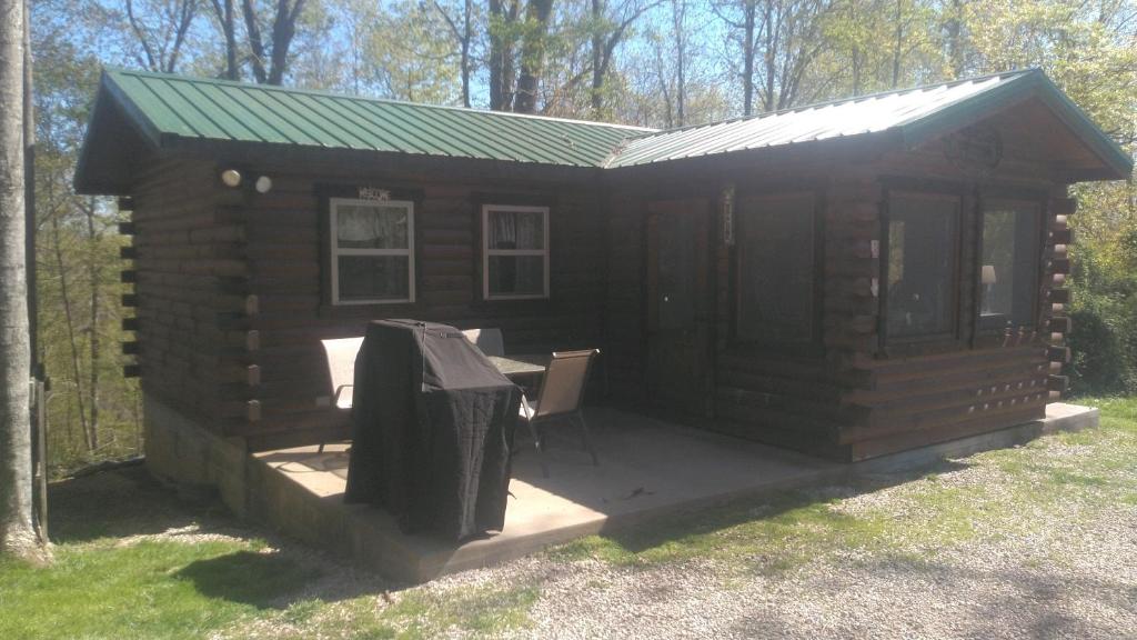 Cabaña de madera con mesa y parrilla en Two Creeks Camp, en Athens