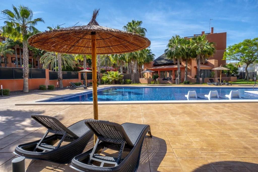 para krzeseł pod parasolem obok basenu w obiekcie Modern 2 Bed Apartment with Com pool VM31 w mieście Orihuela