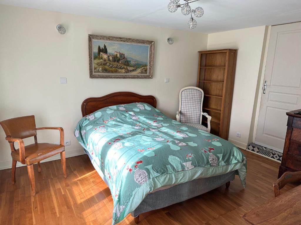 a bedroom with a bed and a chair at Appartement dans résidence calme dans les Monts du Lyonnais in Soucieu-en-Jarrest