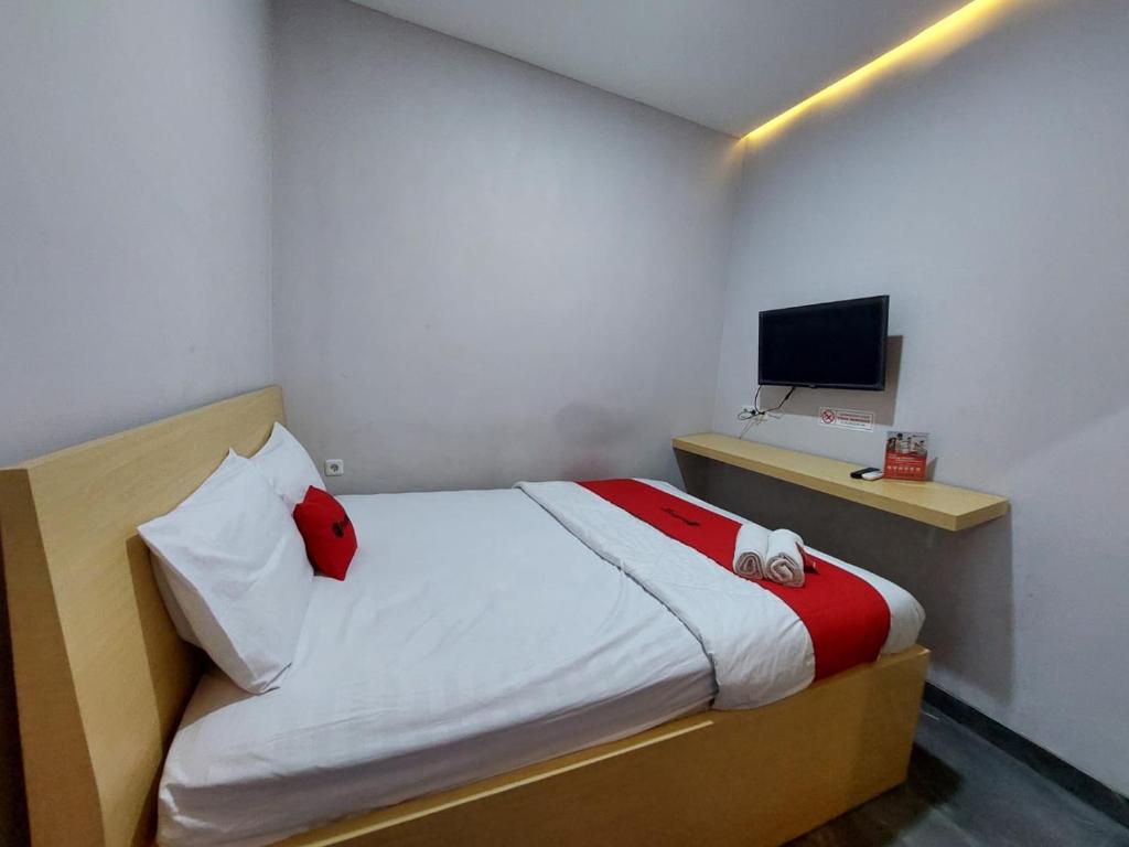 Dormitorio pequeño con cama y TV en Guesthouse Cempaka, en Sibengkok