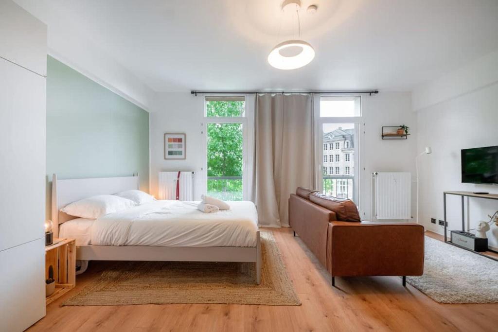 a bedroom with a bed and a couch and a window at Renovated Chic Studio 5 Min to City Center in Luxembourg