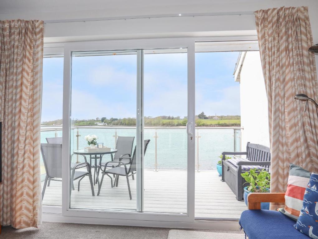 a living room with sliding glass doors with a table and chairs at Waters Edge Ymyl Y Dwr in Y Felinheli