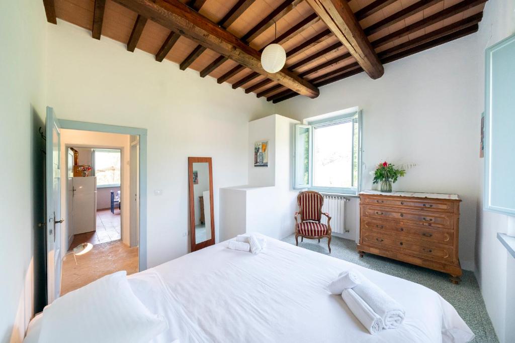 Un dormitorio con una gran cama blanca y una silla. en Agriturismo Brocca, en Tuoro sul Trasimeno