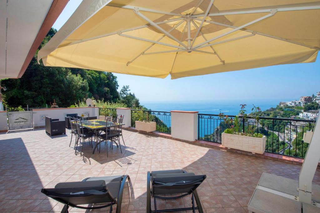 een patio met een tafel en stoelen onder een gele parasol bij La Maison Raffaele & Rita in Amalfi