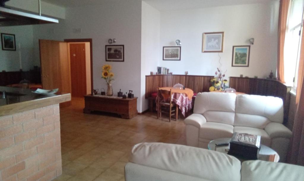 ein Wohnzimmer mit weißen Möbeln und einem Tisch in der Unterkunft Affittacamere al picchio verde in Monsampietro Morico