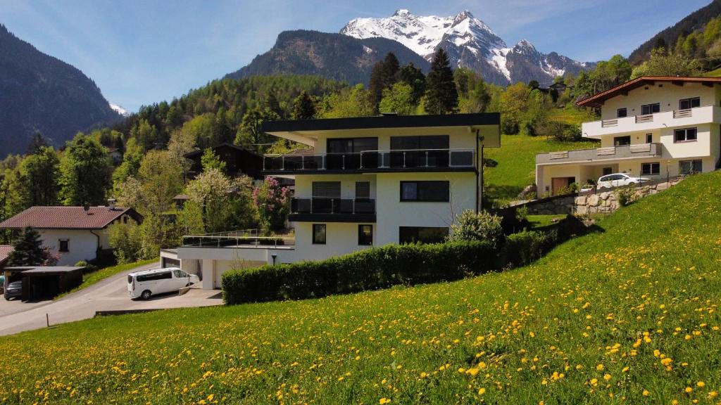 ein Haus auf einem Hügel mit einem Berg im Hintergrund in der Unterkunft MOUNTAIN HOME apartment in Finkenberg