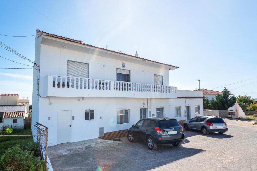 una casa blanca con dos coches aparcados en un estacionamiento en Marya private rooms, en Faro