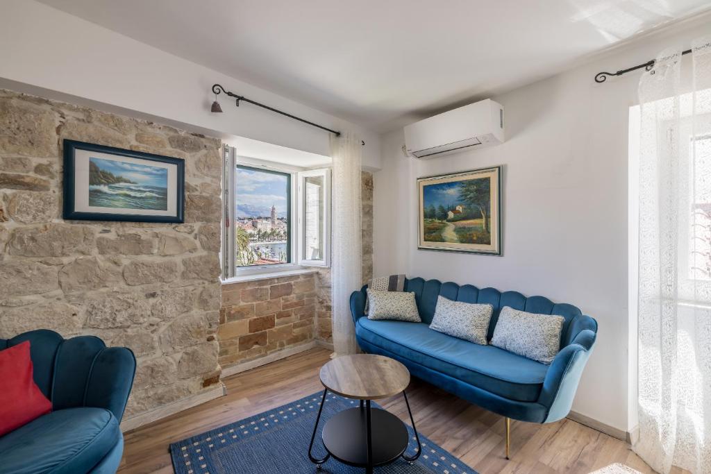 a living room with blue couches and a brick wall at Holiday Home Riva Promenade in Split