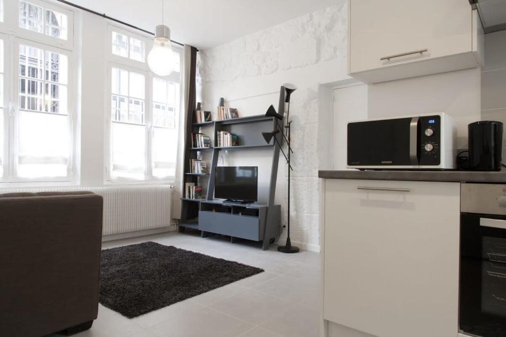 a white kitchen with a microwave and a tv at St Germain des Prés - 2BR - CityApartmentStay in Paris