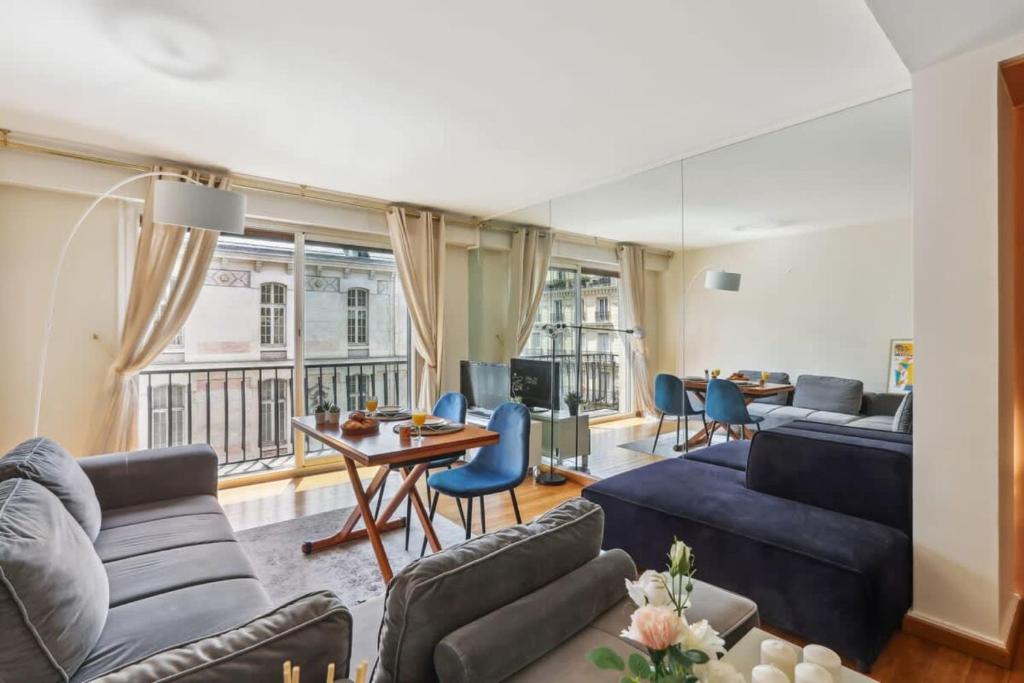 una sala de estar con sofás azules y una mesa. en Trocadero & Arc de Triomphe with Balcony - CityApartmentStay, en París
