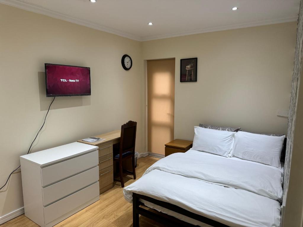 a bedroom with a bed and a desk and a tv at HANDOVER 2 in London
