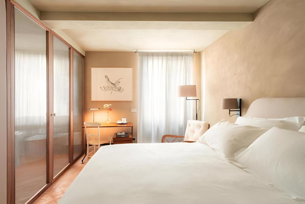 1 dormitorio con 1 cama blanca grande y escritorio en Locanda La Concia, en Reggio Emilia