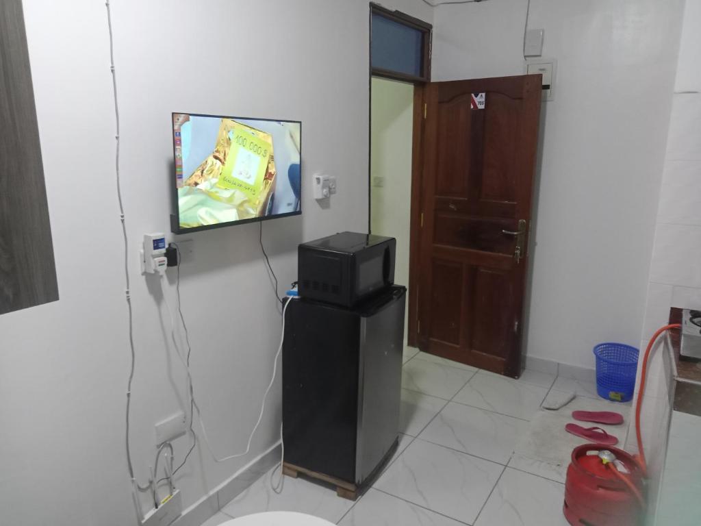 Habitación con TV en la pared y nevera. en Hmy en Mombasa